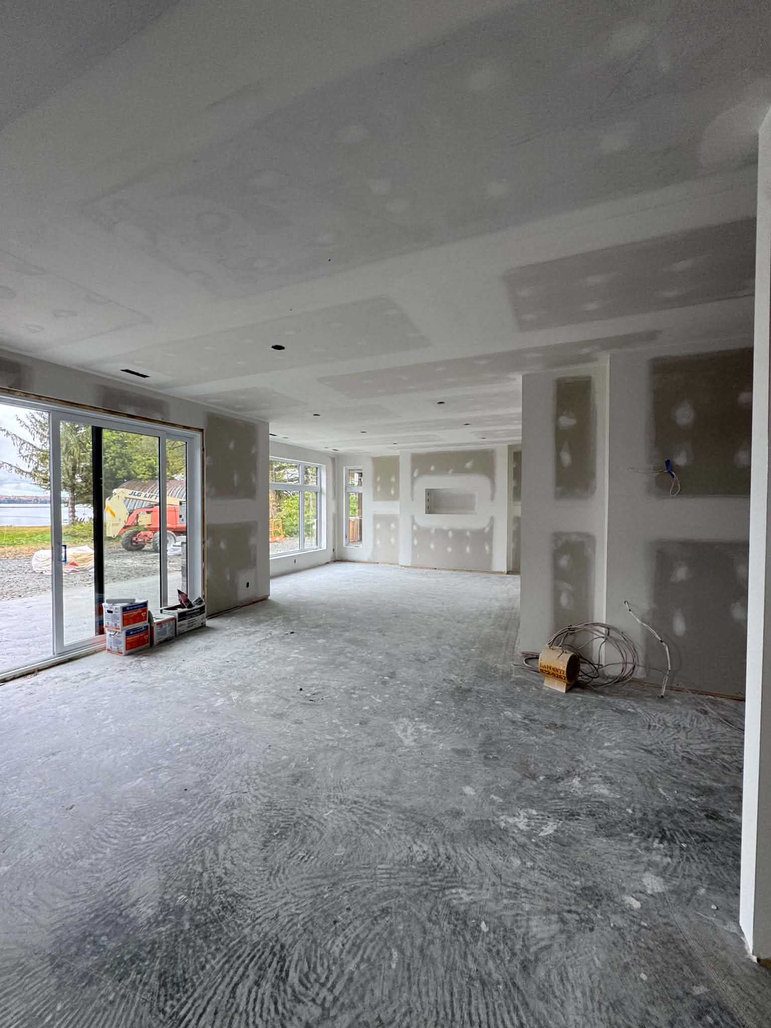 Grande pièce à aire ouverte avec baie vitrée dont les joints de gypse sont en cours de finition